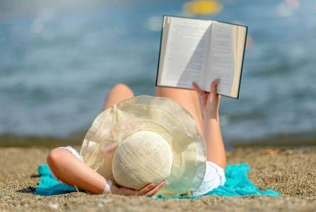 Person reading book on beach